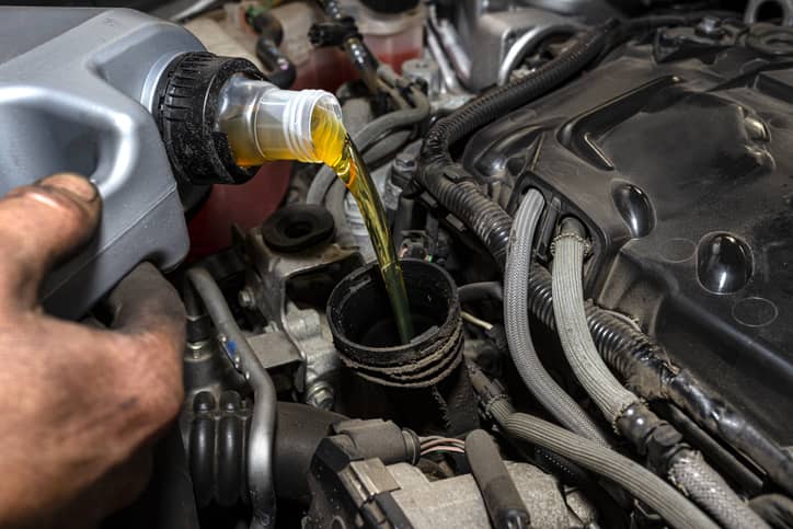 mechanik wlewa olej do silnika samochodu